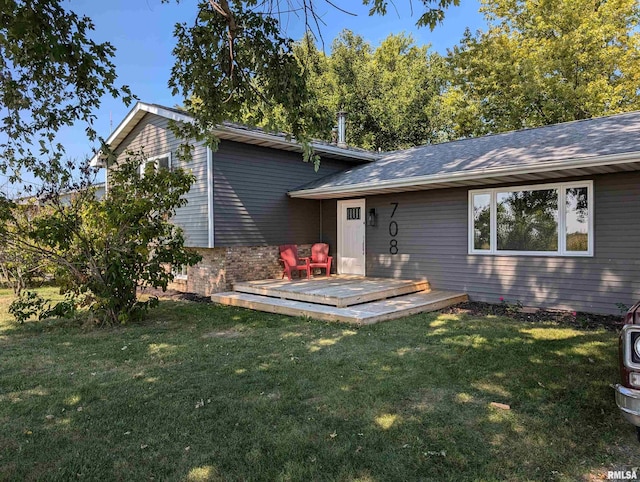 back of house with brick siding, a lawn, and a deck