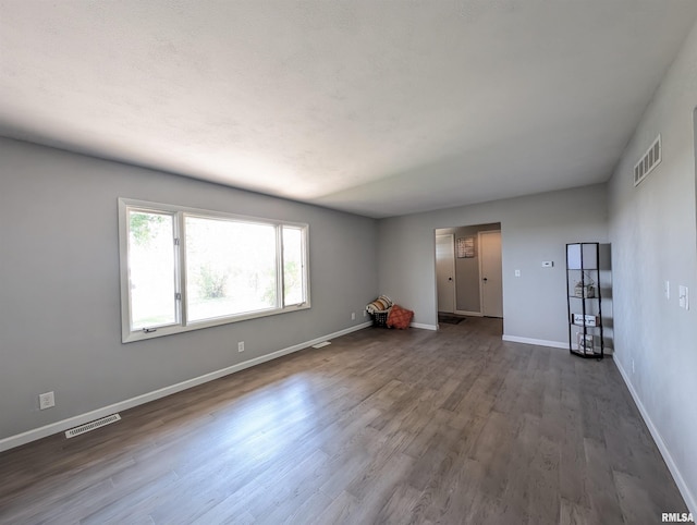 spare room featuring visible vents, baseboards, and wood finished floors