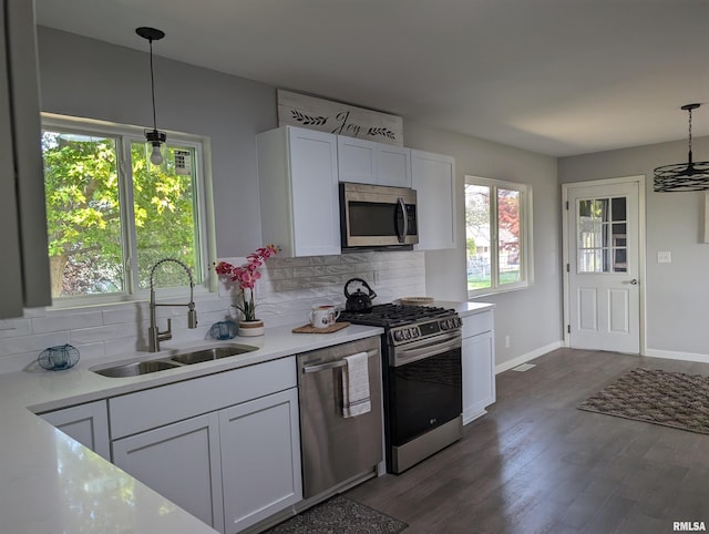 kitchen with pendant lighting, appliances with stainless steel finishes, sink, and white cabinets