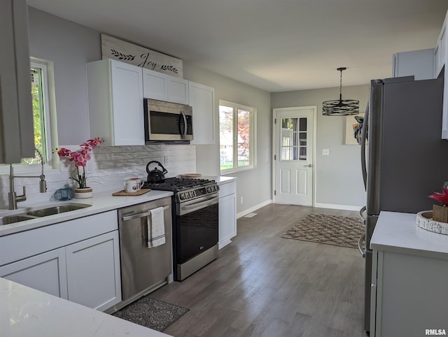 kitchen with white cabinets, wood finished floors, stainless steel appliances, light countertops, and backsplash