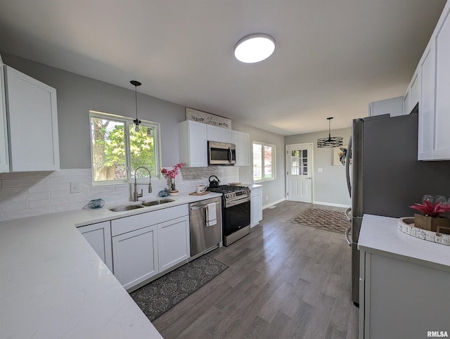 kitchen featuring decorative backsplash, decorative light fixtures, stainless steel appliances, white cabinetry, and a sink