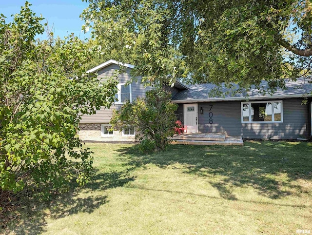 view of front of home featuring brick siding, a wooden deck, and a front lawn