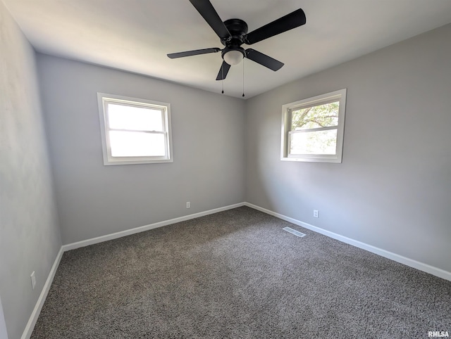 carpeted empty room with ceiling fan, visible vents, and baseboards