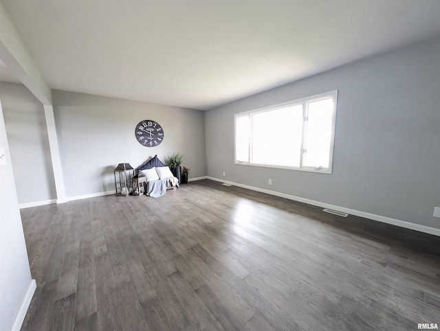 spare room with visible vents, baseboards, and dark wood-style flooring