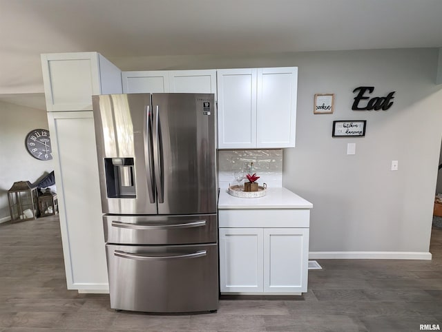 kitchen with white cabinets, tasteful backsplash, dark hardwood / wood-style floors, and stainless steel fridge