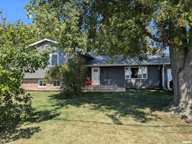 tri-level home featuring a deck, brick siding, and a front yard