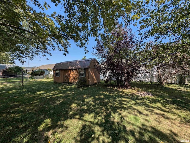 view of yard featuring a storage unit, an outdoor structure, and fence