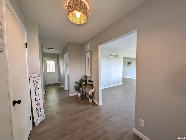 hallway with visible vents, dark wood finished floors, and baseboards