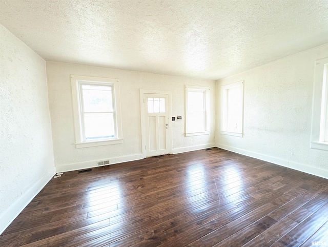 spare room with a textured wall, a textured ceiling, and hardwood / wood-style flooring