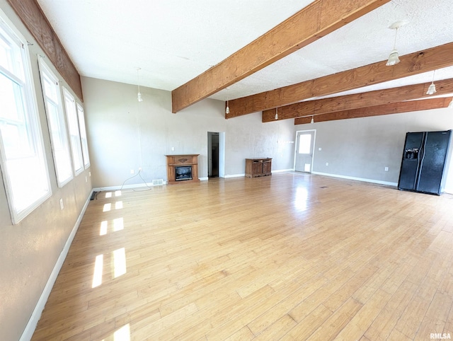 unfurnished living room with beamed ceiling, light hardwood / wood-style floors, and a textured ceiling