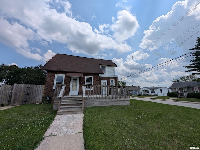 view of front of home featuring brick siding, a front yard, fence, and a wooden deck