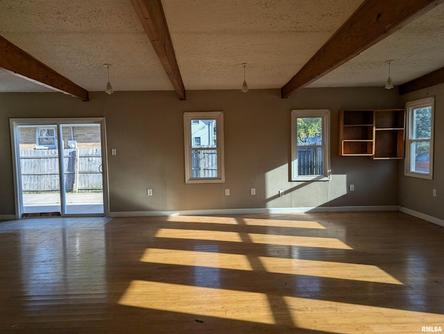 unfurnished living room featuring plenty of natural light, beam ceiling, and an inviting chandelier