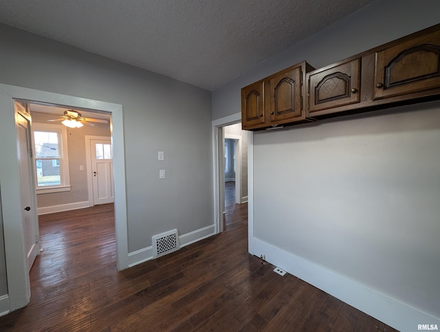 interior space featuring dark wood-style floors, a textured ceiling, visible vents, and baseboards