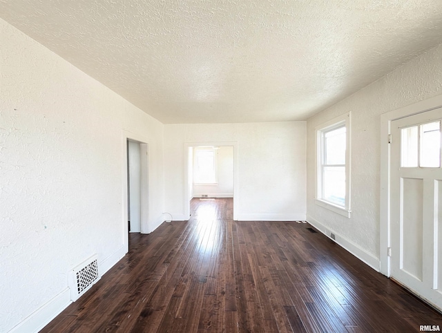 empty room featuring a textured ceiling and dark hardwood / wood-style flooring