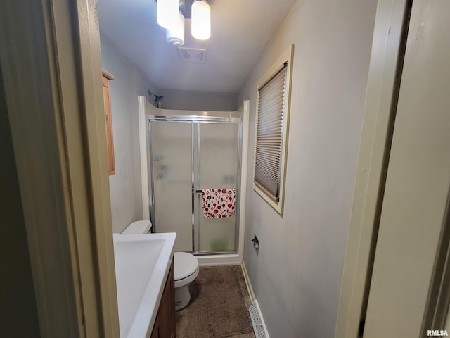 bathroom with vanity, toilet, and a shower with door