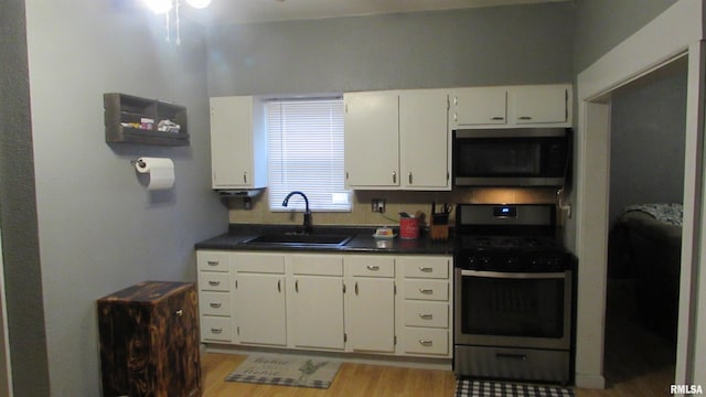 kitchen with white cabinets, sink, appliances with stainless steel finishes, and light hardwood / wood-style flooring