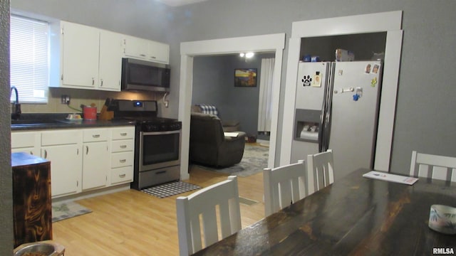 kitchen featuring stainless steel appliances, white cabinetry, and light hardwood / wood-style floors