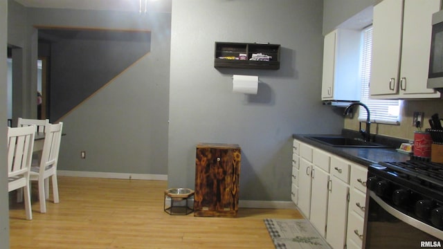 kitchen featuring black gas range, light hardwood / wood-style floors, white cabinetry, and sink