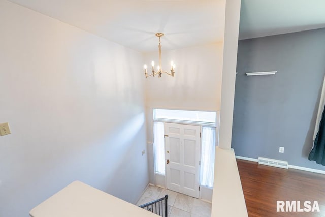 entryway with light hardwood / wood-style flooring and an inviting chandelier