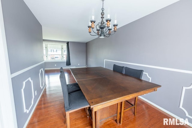 dining space featuring hardwood / wood-style floors and an inviting chandelier