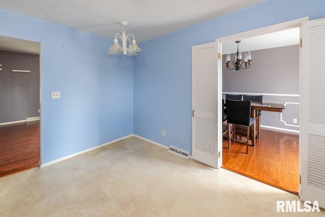 spare room featuring hardwood / wood-style flooring and a notable chandelier