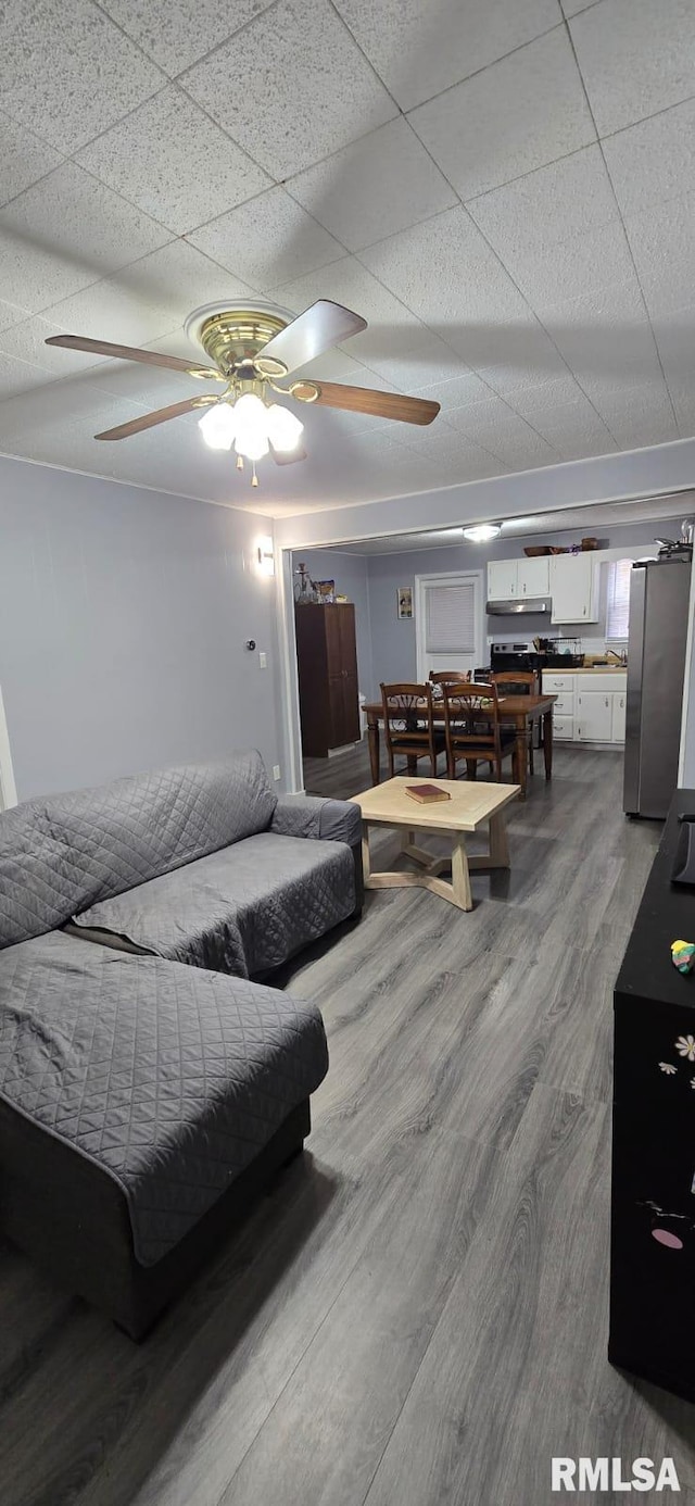 bedroom featuring ceiling fan, a drop ceiling, wood-type flooring, and stainless steel refrigerator