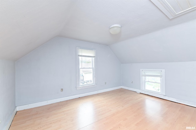 additional living space with vaulted ceiling, plenty of natural light, and wood finished floors