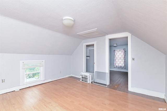 bonus room with a textured ceiling, baseboards, wood finished floors, and lofted ceiling