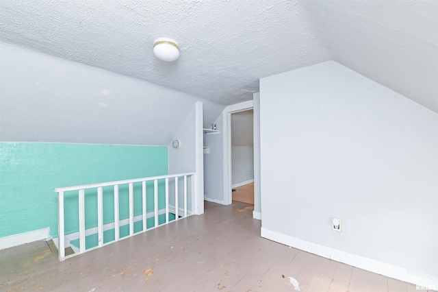 bonus room featuring vaulted ceiling, a textured ceiling, and baseboards