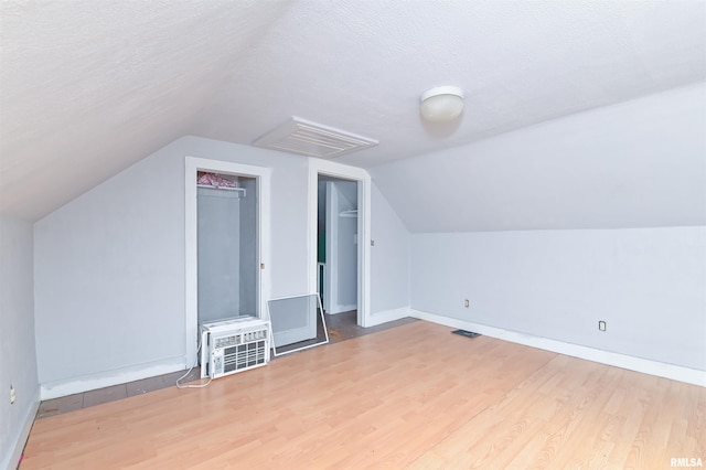 bonus room with a textured ceiling, visible vents, and wood finished floors