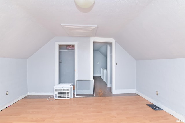 bonus room featuring lofted ceiling, light wood-style floors, and baseboards