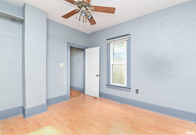 spare room with ceiling fan, light wood-type flooring, and baseboards