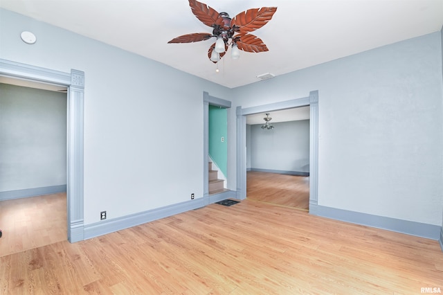 empty room with baseboards, visible vents, ceiling fan, wood finished floors, and stairs