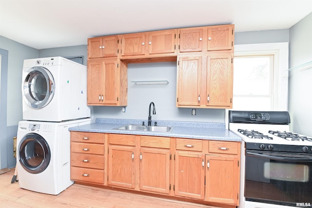 kitchen featuring light countertops, gas stove, a sink, stacked washing maching and dryer, and light wood-type flooring