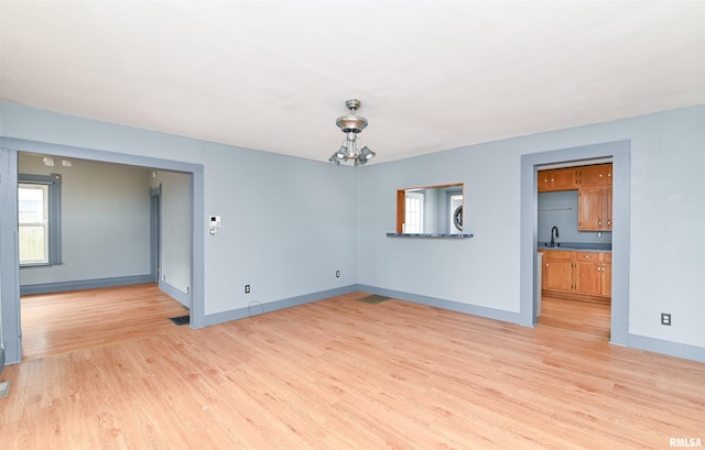 spare room featuring light wood finished floors, plenty of natural light, and baseboards