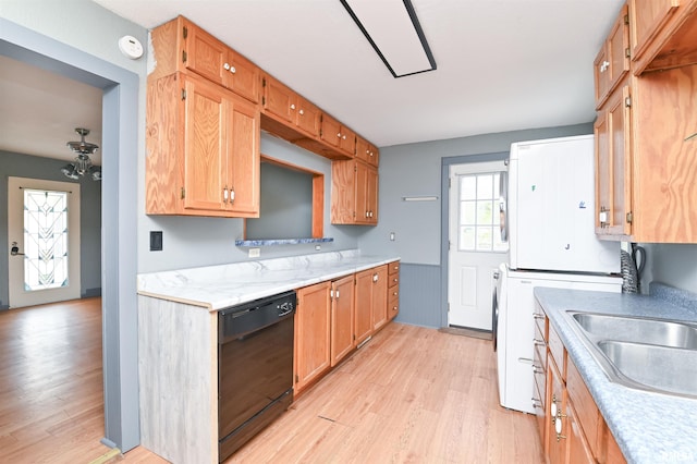 kitchen with black dishwasher, light wood finished floors, light countertops, stove, and a sink