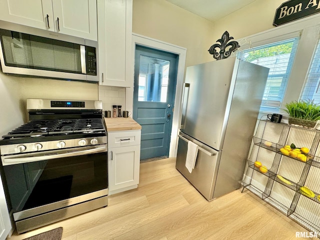 kitchen with plenty of natural light, white cabinets, light hardwood / wood-style flooring, and appliances with stainless steel finishes