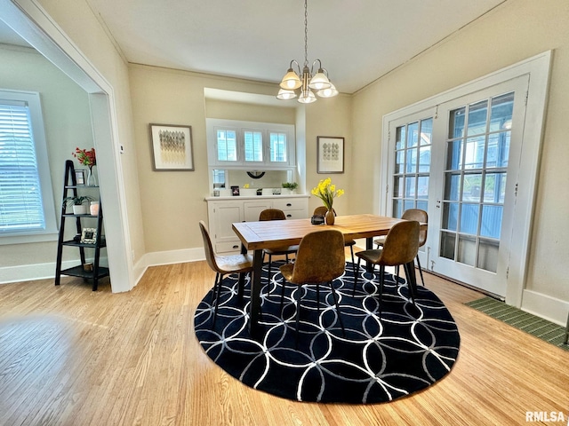 dining room with light wood-type flooring, a wealth of natural light, and a chandelier