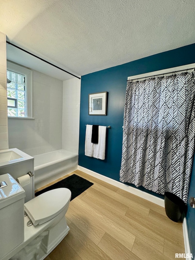 bathroom with a shower with curtain, a textured ceiling, sink, wood-type flooring, and toilet