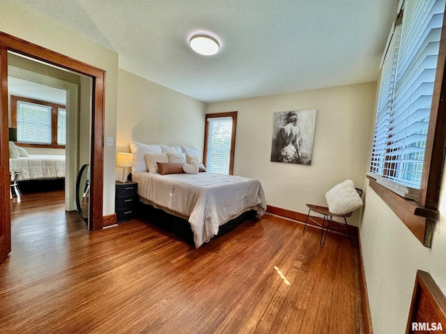 bedroom with hardwood / wood-style flooring and multiple windows