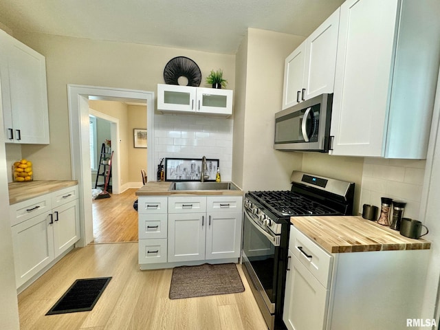 kitchen with white cabinetry, sink, stainless steel appliances, light hardwood / wood-style flooring, and butcher block countertops