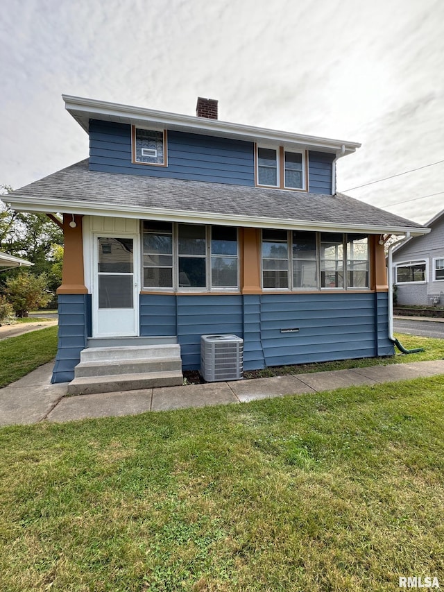 view of front of house with a front lawn and central AC