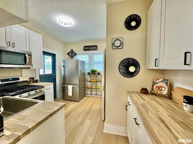 kitchen featuring white cabinets, stainless steel appliances, and butcher block countertops