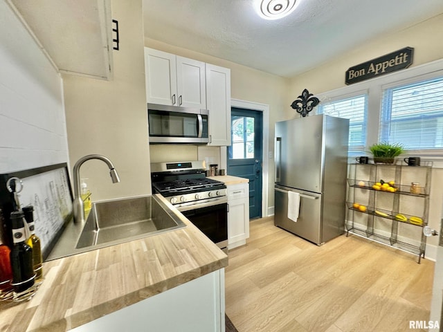 kitchen with white cabinets, appliances with stainless steel finishes, plenty of natural light, and sink