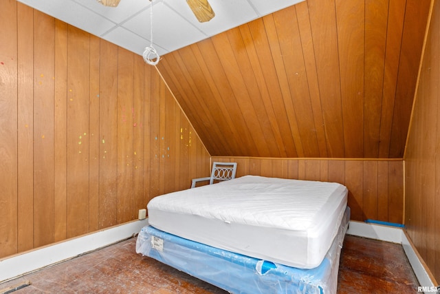 bedroom with ceiling fan, lofted ceiling, and wood walls