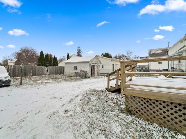 snow covered property with an outbuilding and a wooden deck