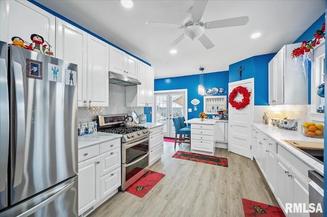 kitchen with appliances with stainless steel finishes, tasteful backsplash, pendant lighting, light hardwood / wood-style floors, and white cabinetry