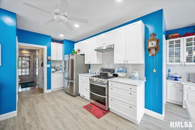 kitchen featuring light wood-type flooring, tasteful backsplash, stainless steel appliances, ceiling fan, and white cabinetry