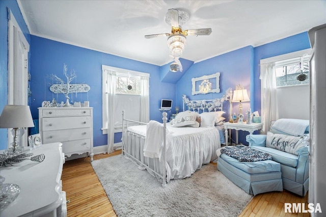 bedroom featuring multiple windows, ceiling fan, crown molding, and hardwood / wood-style flooring