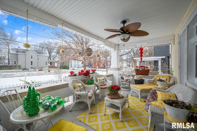 snow covered patio featuring ceiling fan and a porch